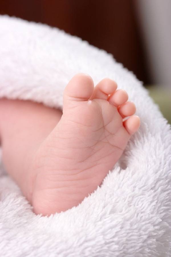 Adorable toddler's foot on white blanket